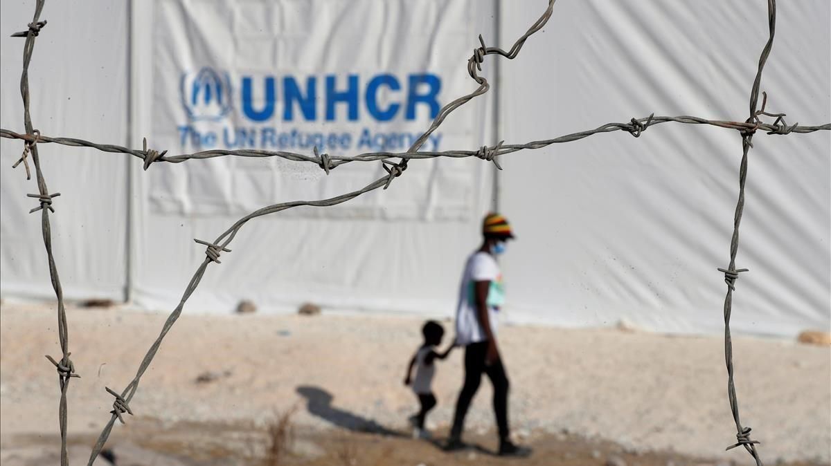 Una mujer y un niño camino tras la reja del nuevo campo de refugiados provisional de Lesbos, en Grecia. Una mujer y un niño camino tras la reja del nuevo campo de refugiados provisional de Lesbos, en Grecia.