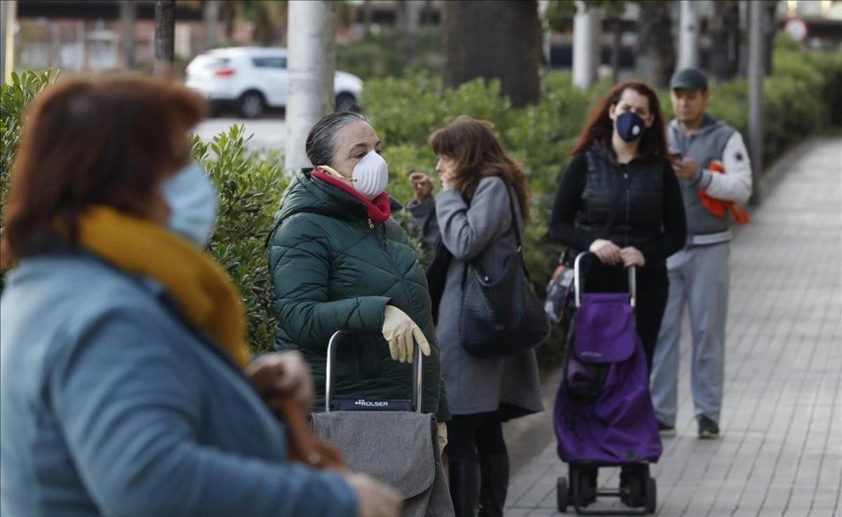 Clientes con mascarilla en la cola de un supermercado en el paseo de la Zona Franca. Clientes con mascarilla en la cola de un supermercado en el paseo de la Zona Franca.