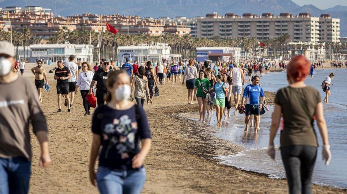 Cientos de ciudadanos dan un paseo por la playa de la Malvarrosa en Valencia.
