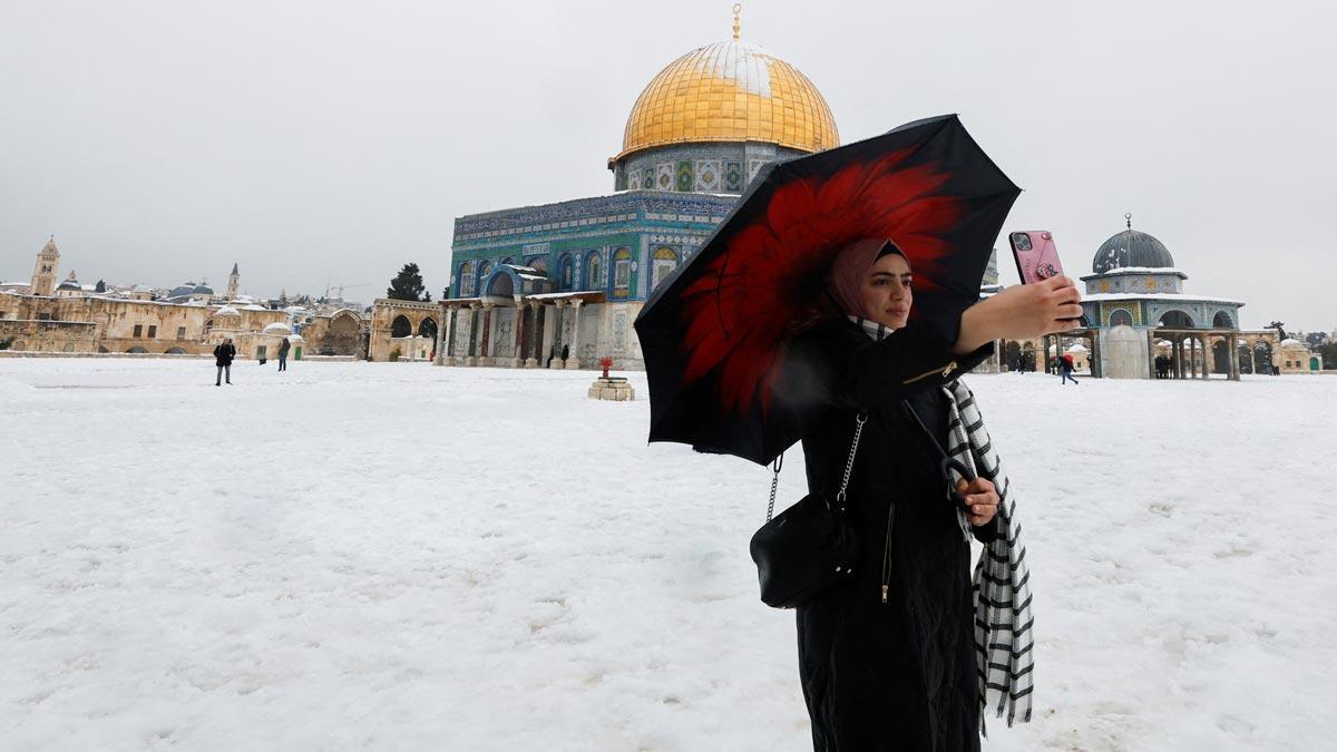 Una mujer se hace un selfi junto a la Cúpula de la Roca, en Jerusalén, tras la intensa nevada.