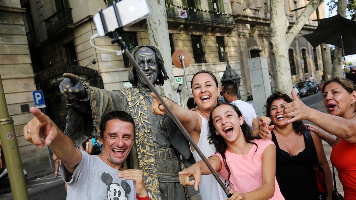 Un grupo se hace un selfi con una estatua humana de la Rambla de  Barcelona, este martes.