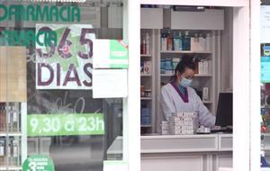 Una empleada de una farmacia de Madrid trabaja con mascarilla.