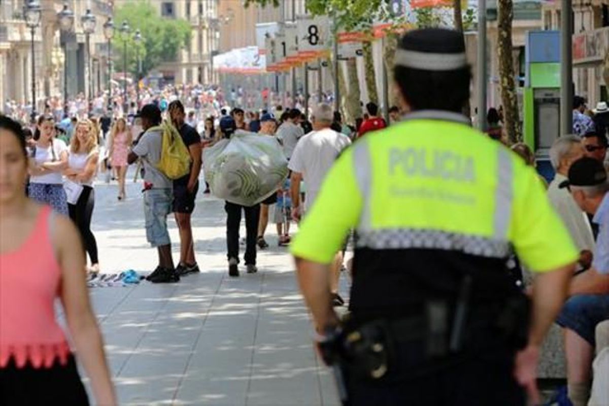 Un guardia urbano se acerca a unos manteros en Portal de l’Àngel, en una imagen de archivo. Un guardia urbano se acerca a unos manteros en Portal de l’Àngel, en una imagen de archivo.