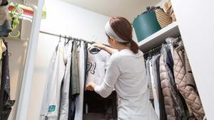 Una mujer ordena ropa en su armario.