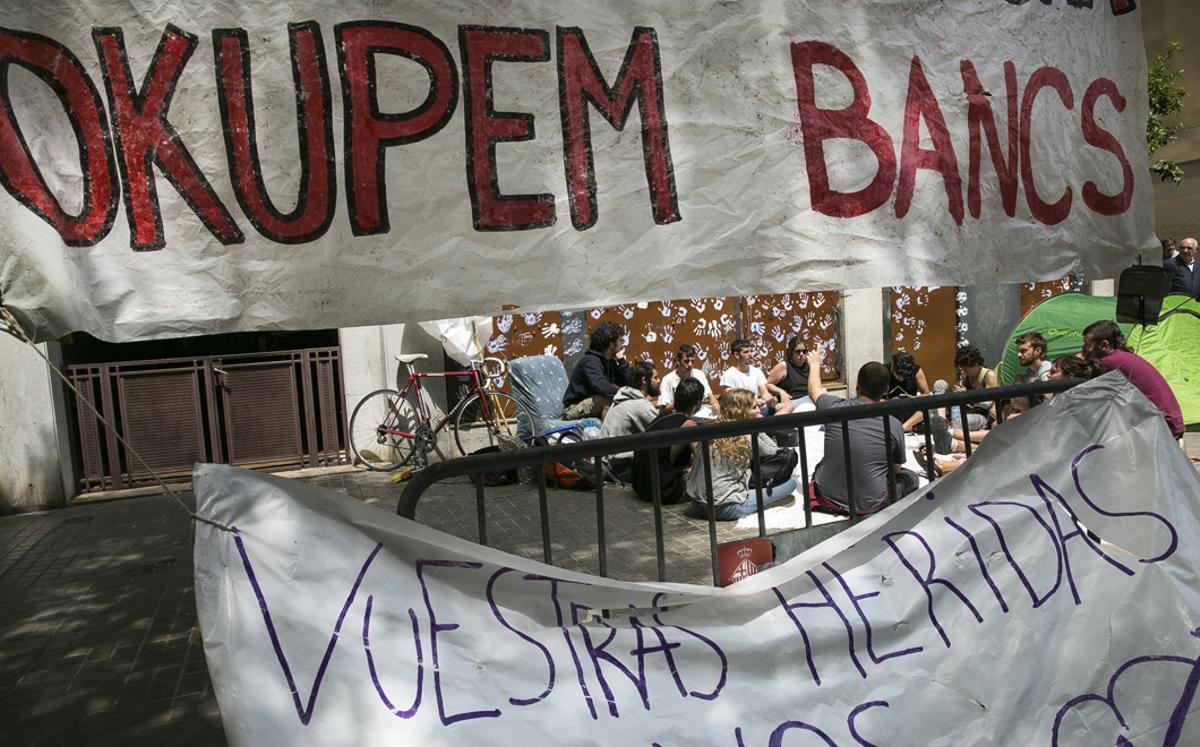 Asamblea de personas afines al movimiento ’okupa’ frente al conocido como banco expropiado’ de la calle Travessera de Gràcia -entonces blindado con paneles metálicos tras el primer desalojo-, el 29 de mayo del 2016. 