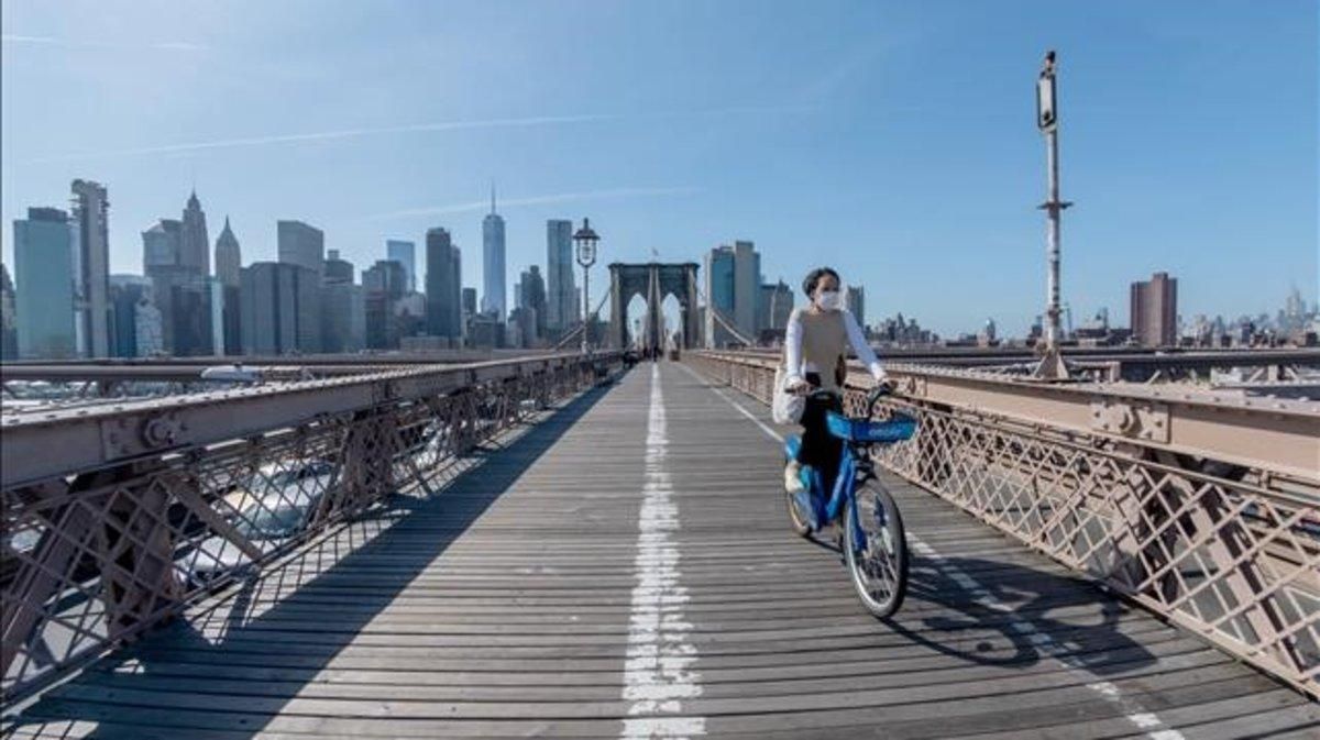 Una ciclista con mascarilla en el puente de Brooklyn de Nueva York. Una ciclista con mascarilla en el puente de Brooklyn de Nueva York.