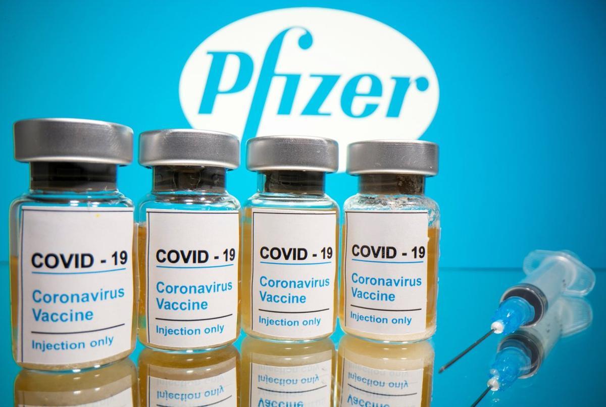 FILE PHOTO: Vials with a sticker reading, COVID-19 / Coronavirus vaccine / Injection only and a medical syringe are seen in front of a displayed Pfizer logo in this illustration taken October 31, 2020. REUTERS/Dado Ruvic/Illustration/File Photo