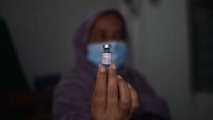 Una mujer sostiene el vial de una vacuna contra el covid-19 durante una jornada de vacunación en Bangladesh. 