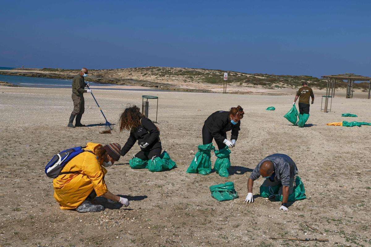 Un grupo de voluntarios israelís limpian de restos de petróleo la playa de  HaBonim, al sur del puerto de la ciudad de Haifa. - 