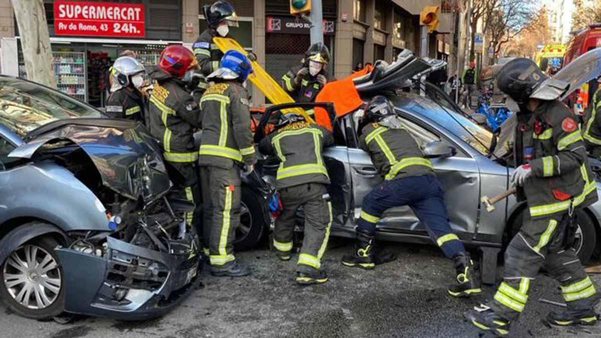 Los bomberos trabajan para liberar a una persona atrapada en su coche, tras un accidente en la calle de Entença, en Barcelona.