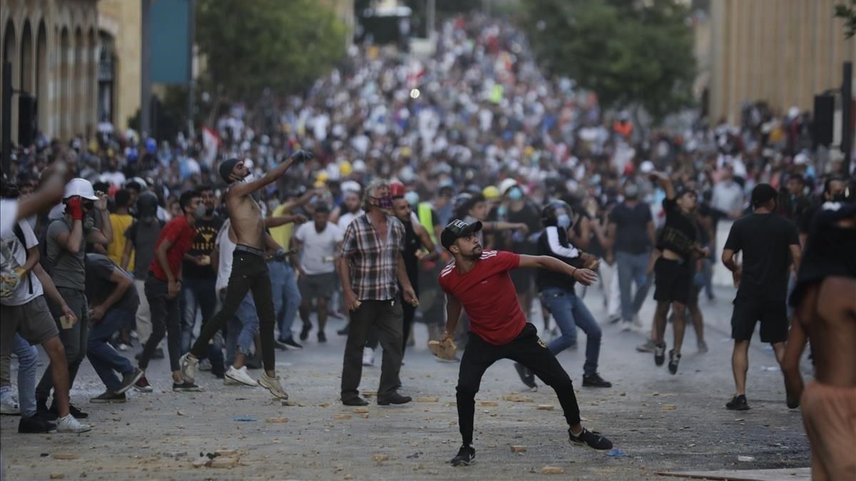 Los manifestantes tiran piedras contra la policía, este domingo en Beirut. Los manifestantes tiran piedras contra la policía, este domingo en Beirut.