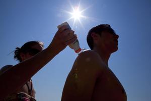 Unos turistas italianos se aplican protección solar en la playa de la Barceloneta 