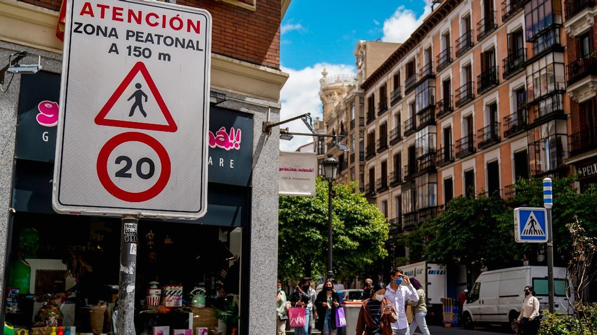 Viandantes pasan al lado de una señal que indica la limitación de la circulación a 20 km/h en una calle de Madrid.