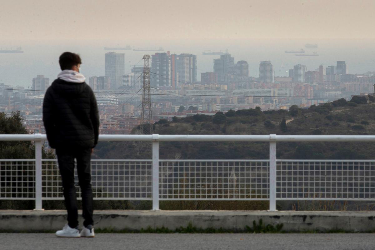 Un joven observa el paisaje de Barcelona en un episodio de alta contaminación por partículas PM10, en una imagen de archivo. EFE/ Enric Fontcuberta.