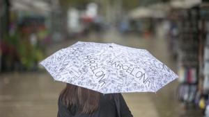 Una mujer con paraguas camina por las Ramblas