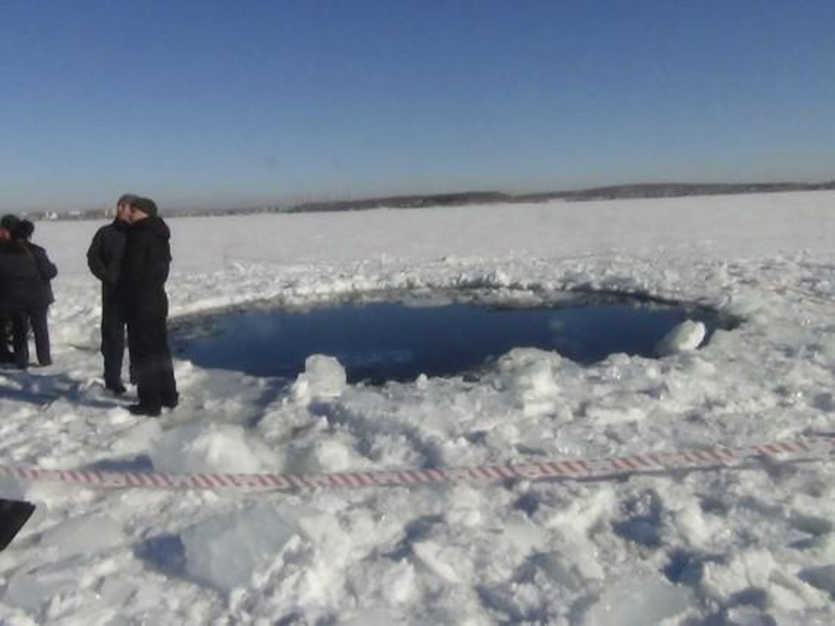 Diversos homes, al costat d’un forat de vuit metres causat per l’impacte del meteorit en un llac congelat de Chelyabinsk. Diversos homes, al costat d’un forat de vuit metres causat per l’impacte del meteorit en un llac congelat de Chelyabinsk.