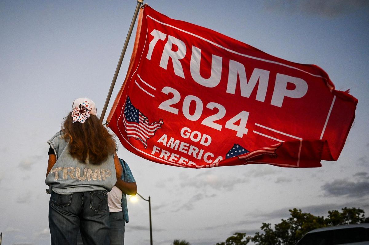 Una partidaria del expresidente estadounidense Donald Trump sostiene una bandera de Trump 2024 mientras protesta cerca del Mar-a-Lago Club en Palm Beach, Florida. Una partidaria del expresidente estadounidense Donald Trump sostiene una bandera de Trump 2024 mientras protesta cerca del Mar-a-Lago Club en Palm Beach, Florida.