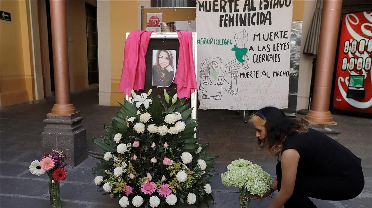 Una mujer coloca flores el miércoles frente a la fotografía de Ingrid Escamilla, una joven de 25 años, víctima de un feminicidio en Puebla.