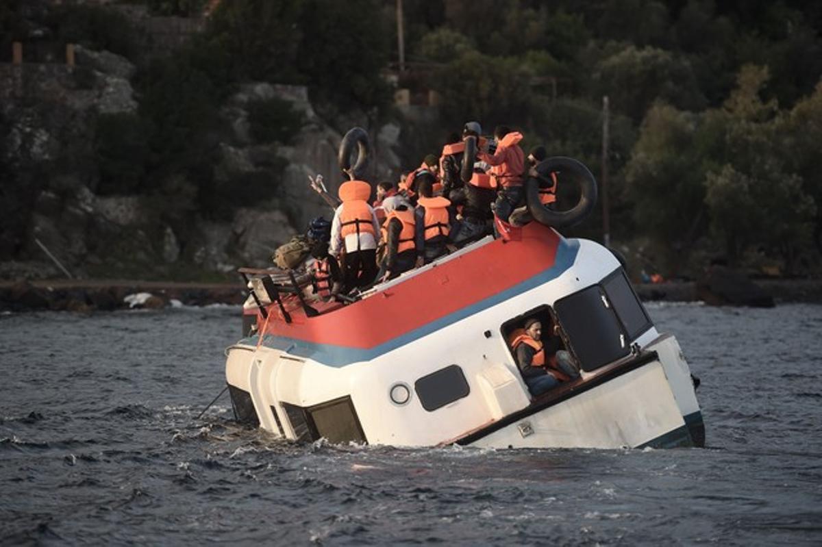 Los inmigrantes se colocan en lo alto de la embarcación a la espera de ser rescatados.