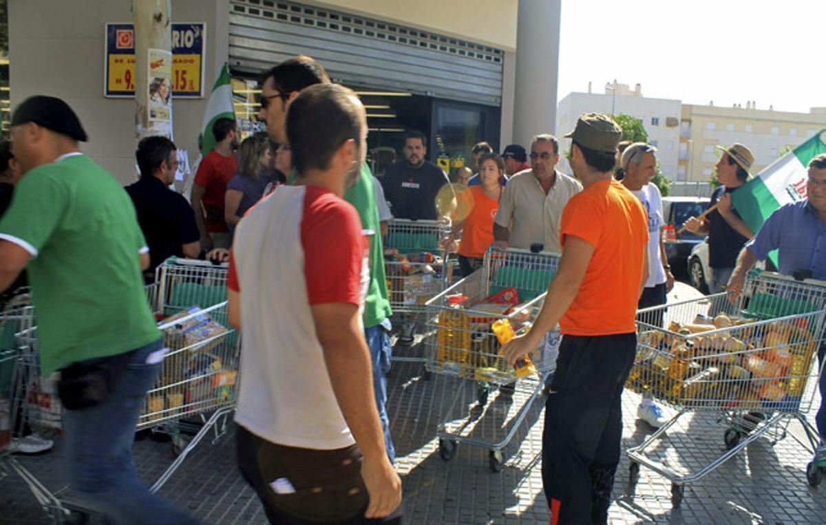 Miembros del Sindicato Andaluz de Trabajadores, el martes en Écija (Sevilla), durante el asalto a un supermercado. Miembros del Sindicato Andaluz de Trabajadores, el martes en Écija (Sevilla), durante el asalto a un supermercado.