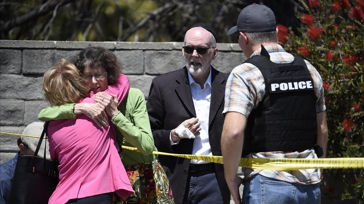 Dos personas se abrazan en la zona acordonada de la sinagoga de Powayn (California, EEUU), donde ha habido un tiroteo este sábado. Dos personas se abrazan en la zona acordonada de la sinagoga de Powayn (California, EEUU), donde ha habido un tiroteo este sábado.