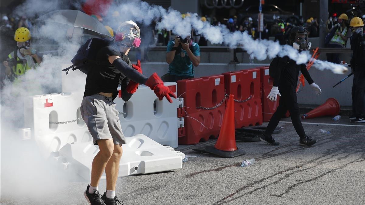Un manifestante lanza a la policía un bote de gas lacrimógeno.