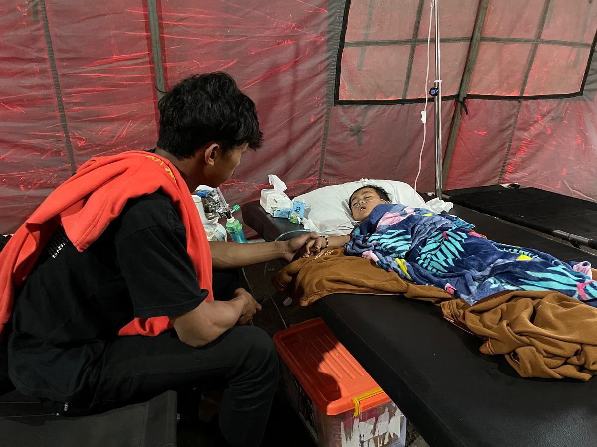 Salman Alfarisi, de 22 años, se sienta junto a su hermano pequeño Azka, de seis años, en una tienda de campaña de emergencia fuera del hospital en Cianjur, Indonesia.
