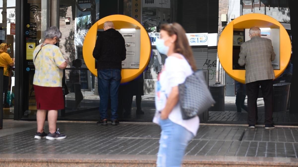 Varias personas sacan efectivo en un cajero en una oficina bancaria en Barcelona. Varias personas sacan efectivo en un cajero en una oficina bancaria en Barcelona.