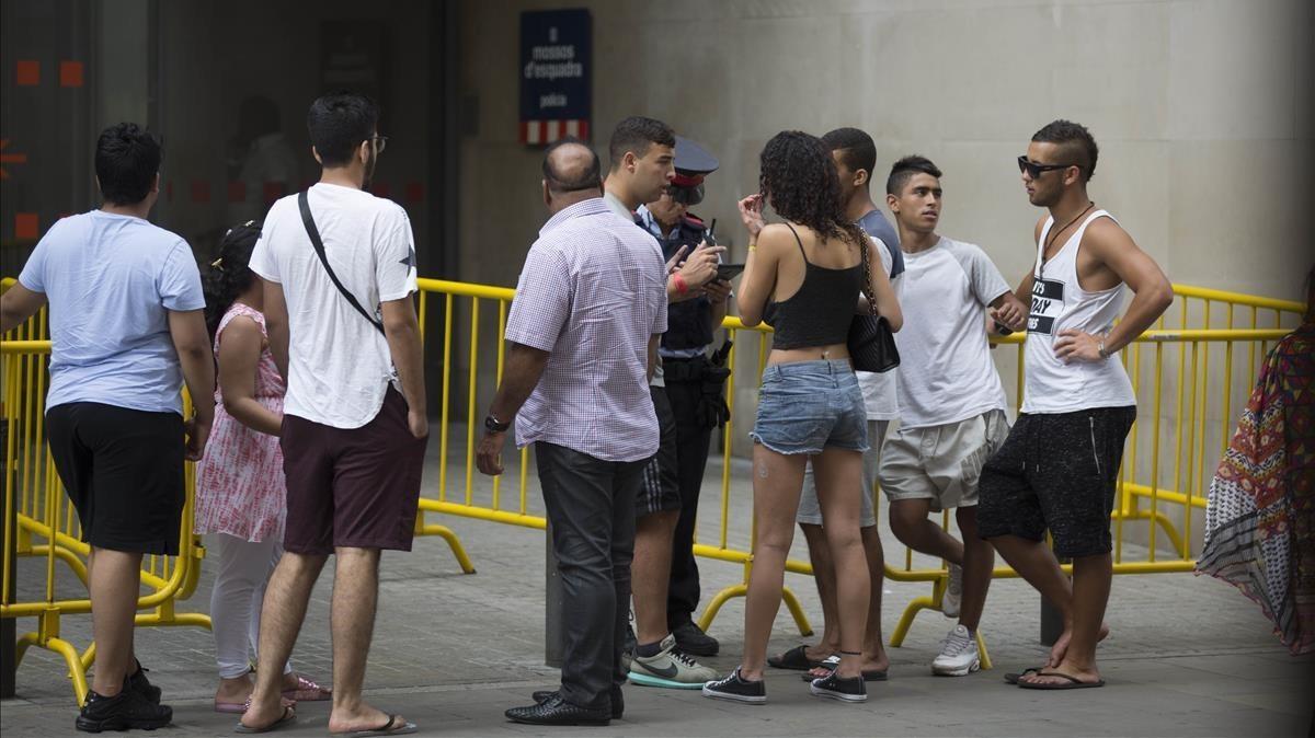 Una agente informa a los ciudadanos en la entrada de la comisaría de Ciutat Vella de Barcelona que hay tres horas de cola para denunciar un delito, el pasado jueves al mediodía. Una agente informa a los ciudadanos en la entrada de la comisaría de Ciutat Vella de Barcelona que hay tres horas de cola para denunciar un delito, el pasado jueves al mediodía.