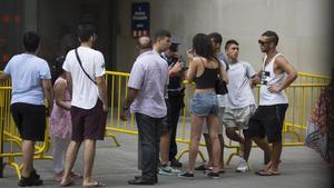 Una agente informa a los ciudadanos en la entrada de la comisaría de Ciutat Vella de Barcelona que hay tres horas de cola para denunciar un delito, el pasado jueves al mediodía. 