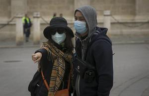 Turistas con mascarillas para protegerse del coronavirus pasean por Sevilla.