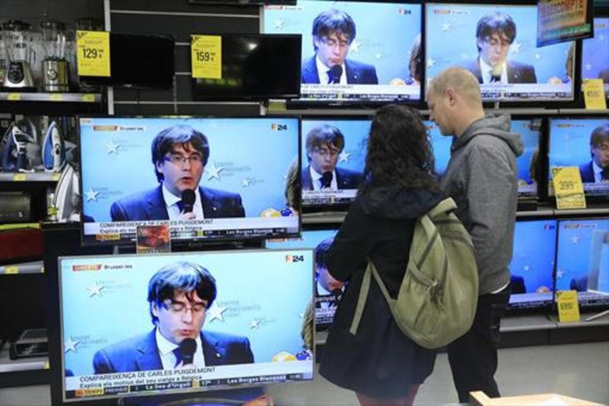 Expectación 8 Una pareja sigue la rueda de prensa de Puigdemont en una tienda del Poblenou. Expectación 8 Una pareja sigue la rueda de prensa de Puigdemont en una tienda del Poblenou.