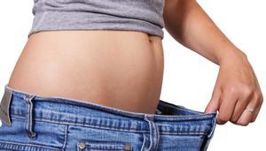Una mujer sujeta su pantalón tras hacer dieta. 