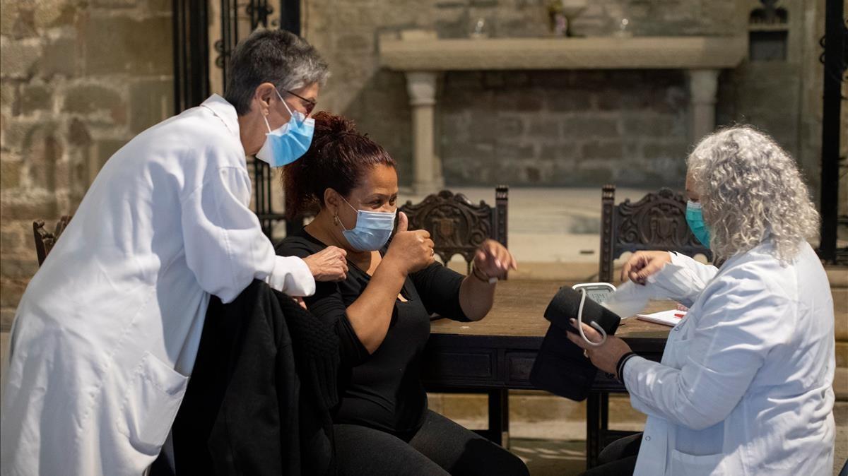Una mujer es atendida por dos sanitarias en la parroquia de Santa Anna de Barcelona, en noviembre de 2020.