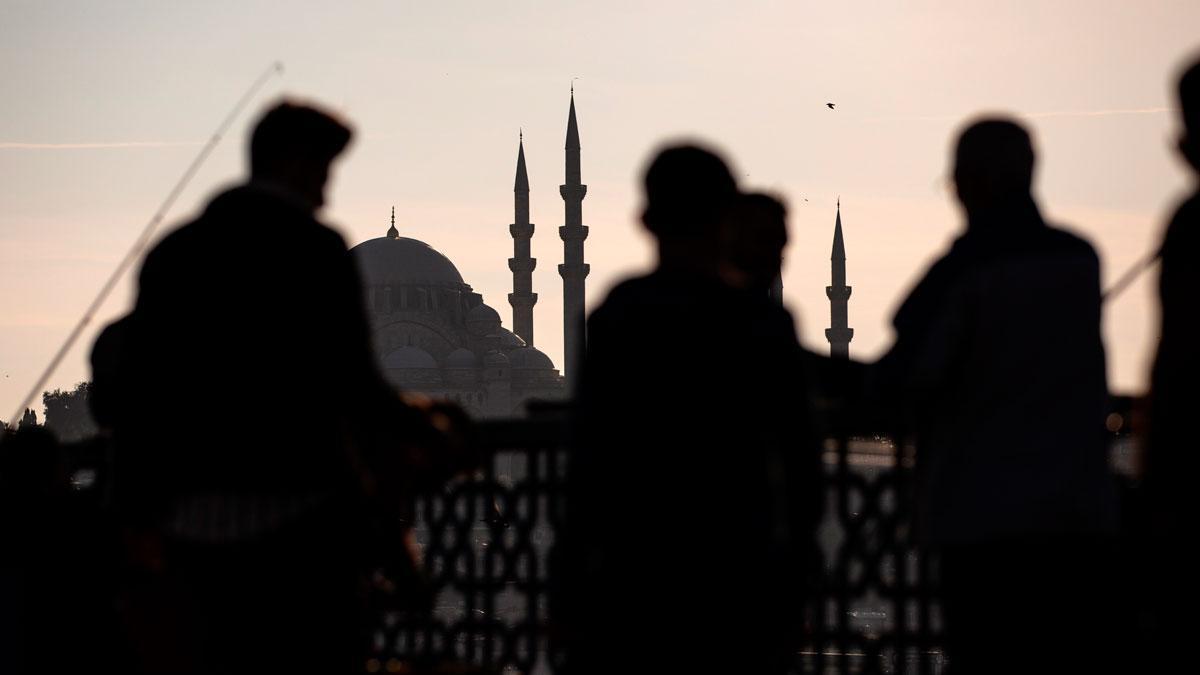 Varias personas caminan junto al puente de Galata, frente a la mezquita de Suleimán, en Estambul.