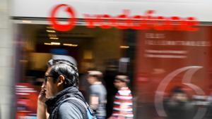 Personas pasan por delante de una tienda de Vodafone en Barcelona.