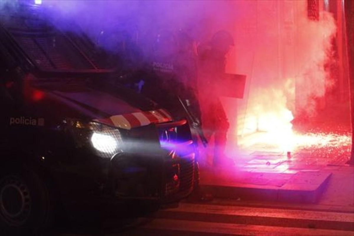 Varios mossos intentan sofocar uno de los incendios provocados en Gràcia. Varios mossos intentan sofocar uno de los incendios provocados en Gràcia.