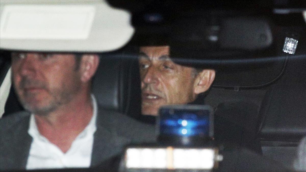 Nicolas Sarkozy  abandona en el interior de un automovil la comisaría de policía en Nanterre, a las afueras de París, donde ha declarado.