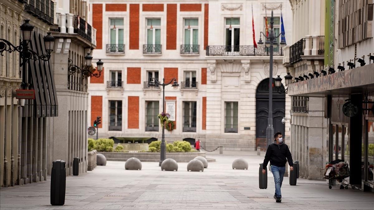 Un hombre camina por la Calle Preciados de Madrid, completamente vacía durante el confinamiento 