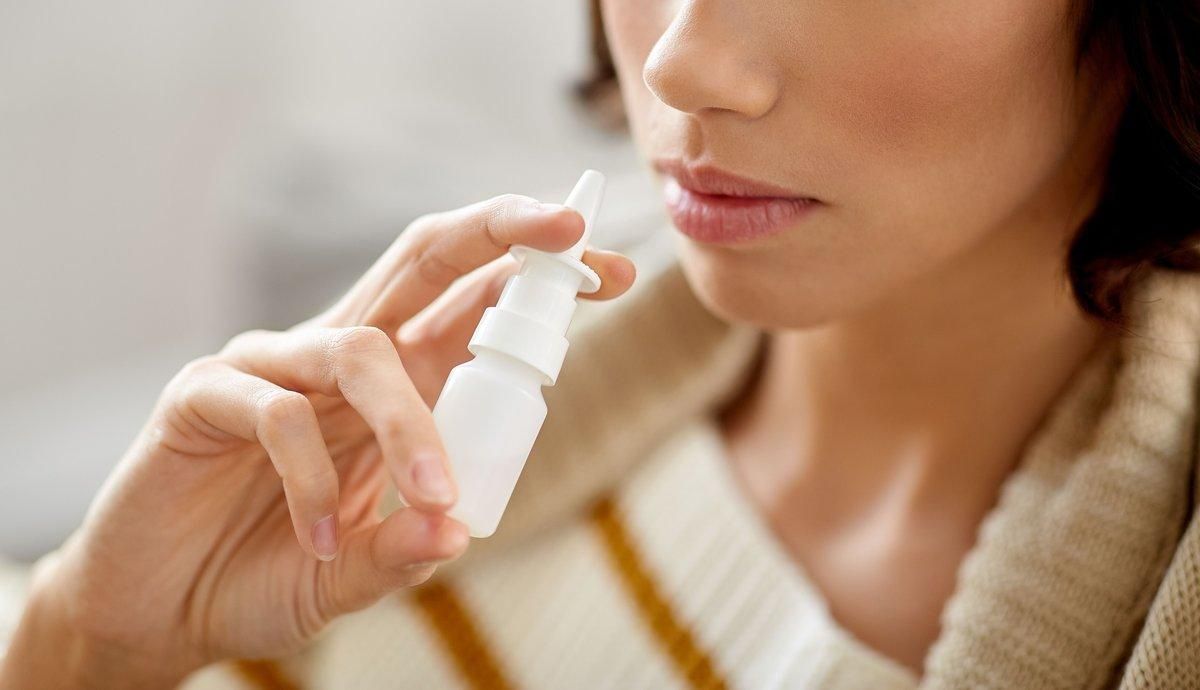 Una mujer se aplica un espray nasal. Una mujer se aplica un espray nasal.