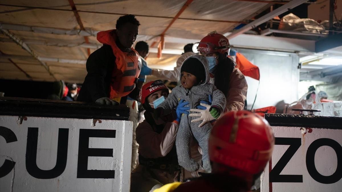Miembros de la tripulación del ’Open Arms’ ayudan a subir a bordo del barco a un bebé rescatado. Miembros de la tripulación del ’Open Arms’ ayudan a subir a bordo del barco a un bebé rescatado.