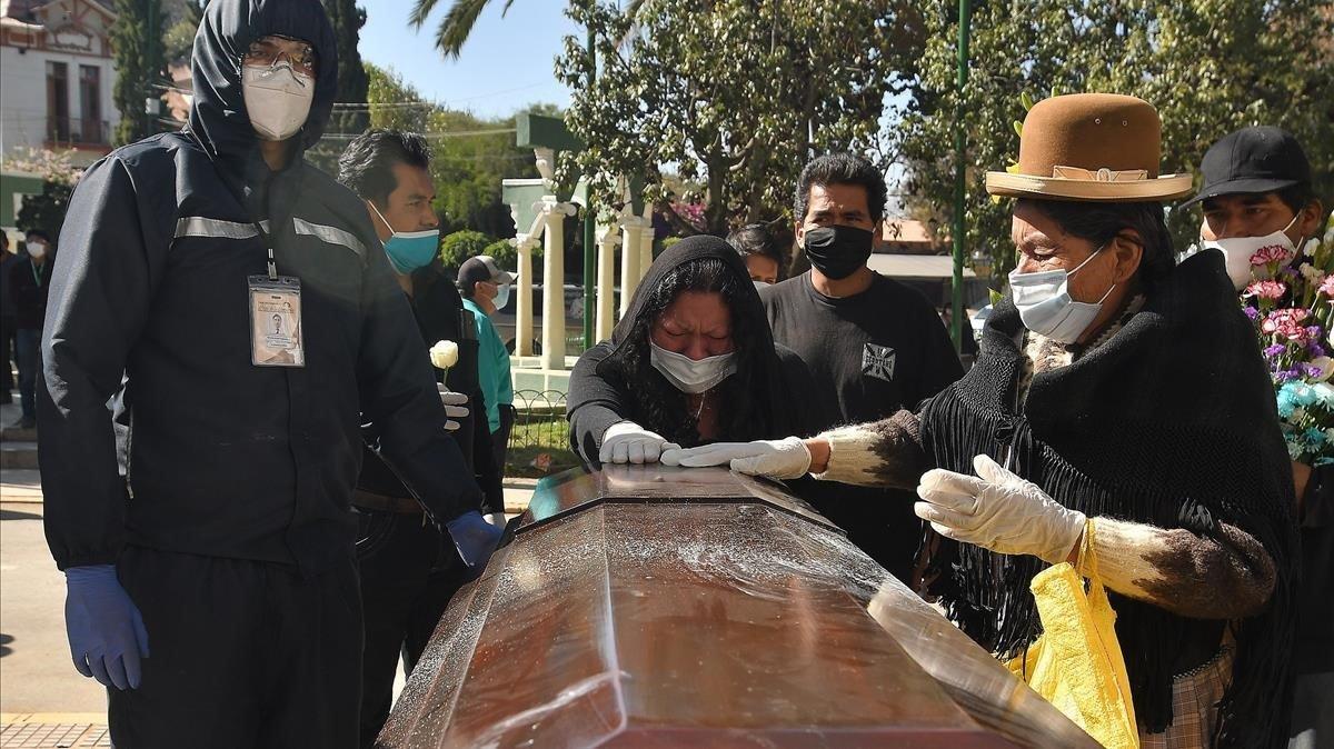 Despedida de dos mujeres a su familiar fallecido a las puertas del cementerio general de Cochabamba, este miércoles.