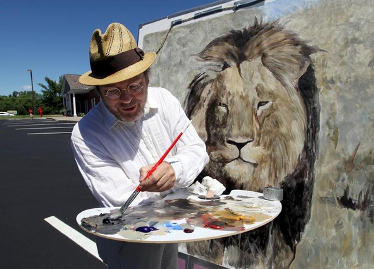 El artista californiano Mark Balma pinta a Cecil ante la clínica del dentista Walter James Palmer, este miércoles.