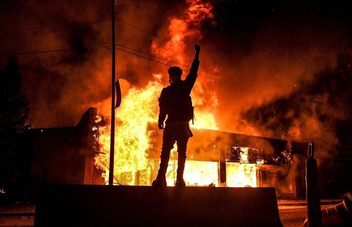 Un manifestante, frente a un edificio en llamas durante la manifestación en Minneapolis. 