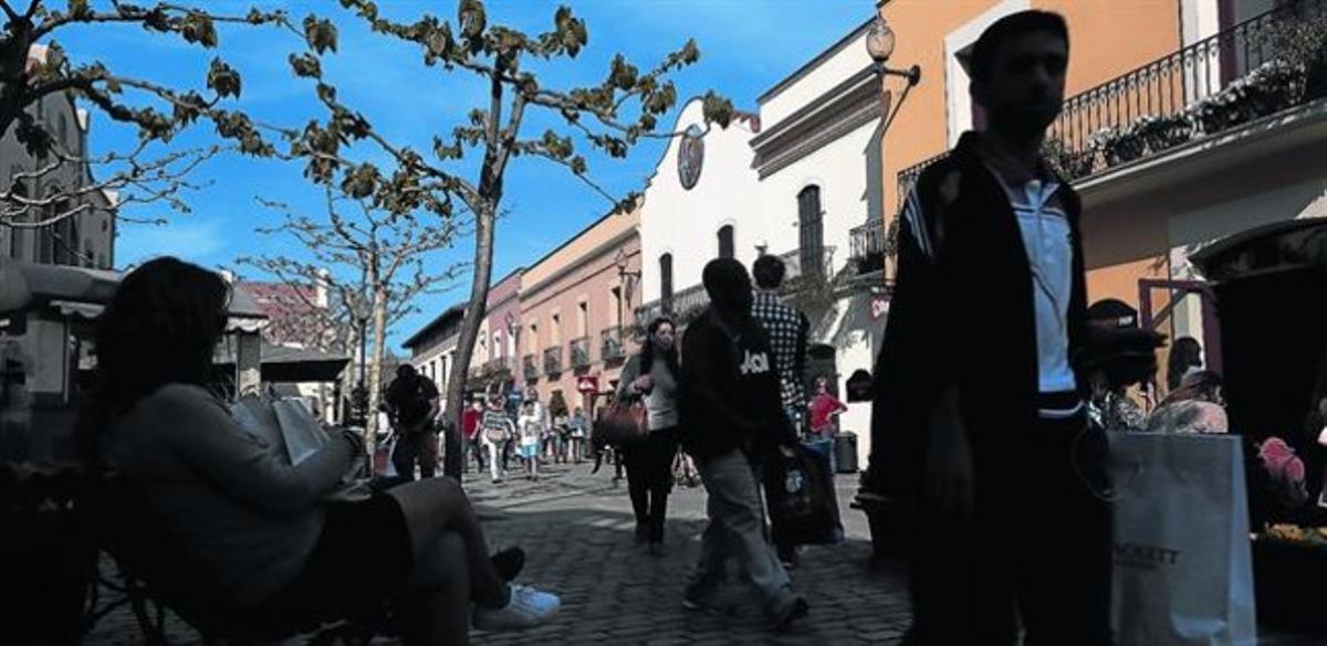 Clientes del ’outlet’ La Roca Village pasean por la calle principal del centro comercial del Vallès Oriental, ayer.