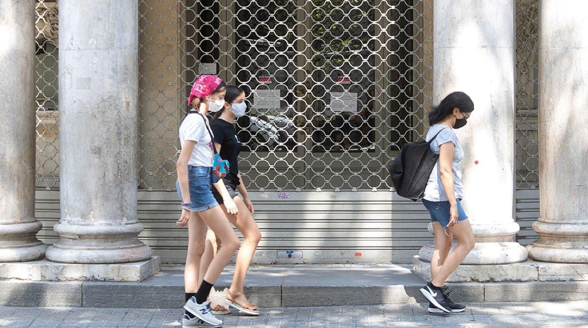 Un grupo de jóvenes pasan por delante del Teatre Coliseum de Barcelona, nuevamente cerrado por los rebrotes de coronavirus, el lunes 27 de julio. Un grupo de jóvenes pasan por delante del Teatre Coliseum de Barcelona, nuevamente cerrado por los rebrotes de coronavirus, el lunes 27 de julio.