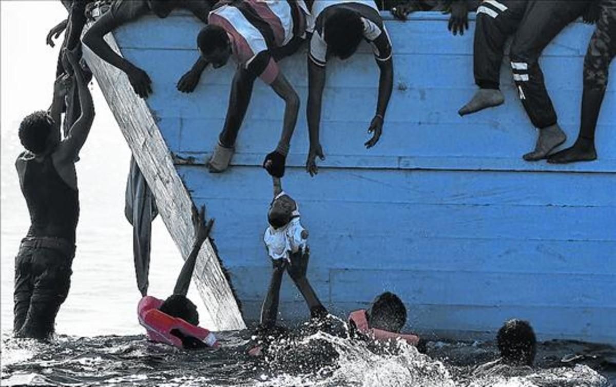 Unos inmigrantes tratan de sacar a un niño del mar frente a las costas de Libia, en una foto de archivo. Unos inmigrantes tratan de sacar a un niño del mar frente a las costas de Libia, en una foto de archivo.