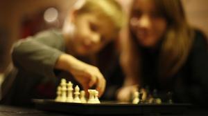 Un niño superdotado juega con su madre al ajedrez.