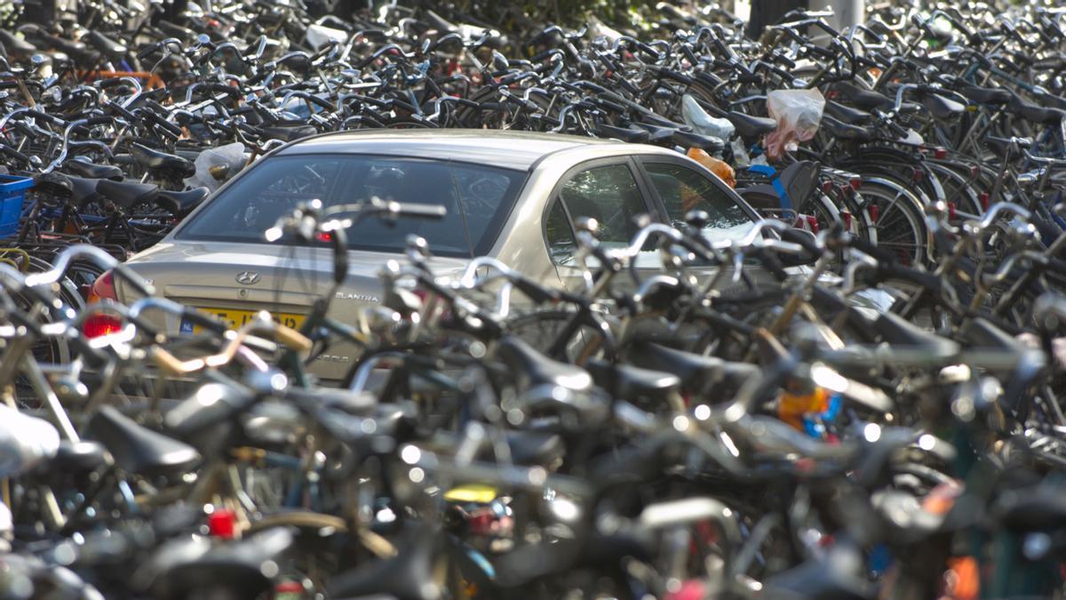 La silueta de un coche emerge entre un mar de bicicletas en el aparcamiento de la estación central de trenes de Amsterdam.