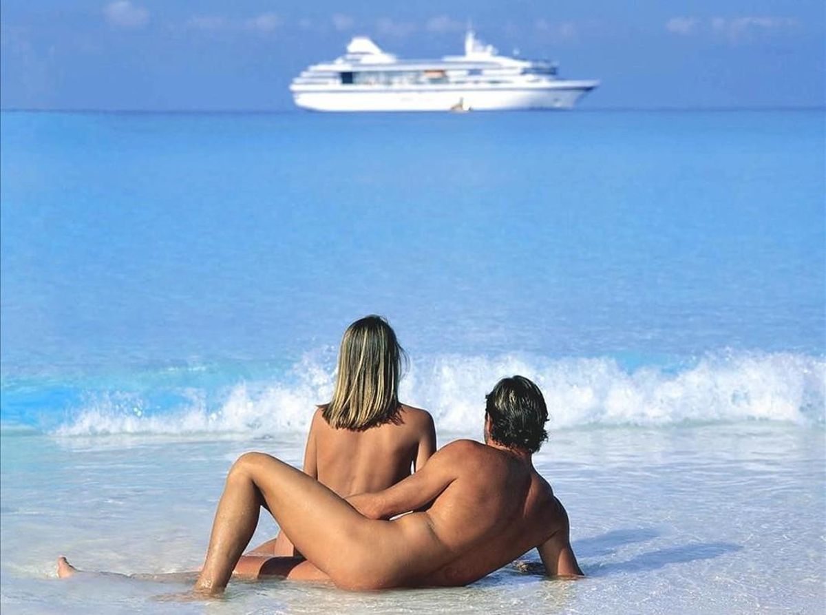 Una pareja practica nudismo en una playa de un complejo de vacaciones de lujo. Una pareja practica nudismo en una playa de un complejo de vacaciones de lujo.